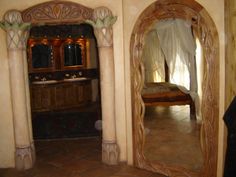 an ornately decorated bathroom with large mirror and tub in the corner, next to a bed