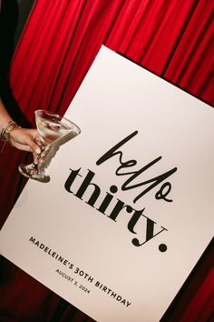 a woman holding up a sign that says helle thry with a martini in it