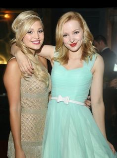 two young women standing next to each other at a formal event, posing for the camera