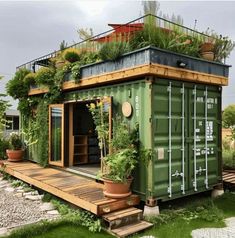 a green shipping container with plants growing on top and stairs leading up to the roof