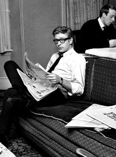 a man sitting on a couch reading a newspaper