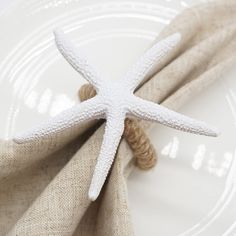 a white starfish sitting on top of a plate next to a cloth covered napkin