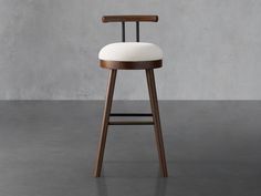 a wooden stool with white upholstered seat and backrest in front of a concrete wall