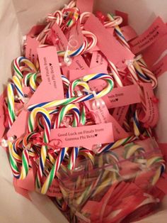 a box filled with lots of candy canes and tags that say good luck on ribbons