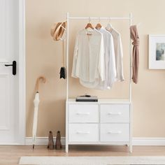 an open white closet with clothes hanging on the rail and hat rack next to it