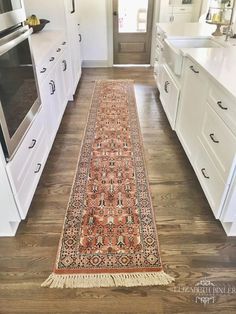 a long rug is in the middle of a kitchen with white cabinets and drawers on both sides