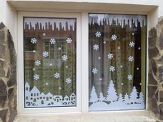 the window is decorated with snowflakes and trees in front of stone walling