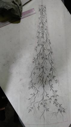 a piece of paper that has been drawn with flowers and vines on it, sitting on top of a table