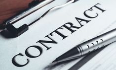 a close up of a paper with the word contract on it and two pens laying next to it