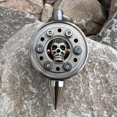 a skull head is attached to the side of a fishing reel on top of some rocks