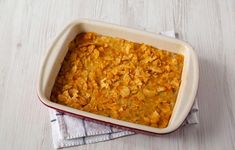 a casserole dish filled with food sitting on top of a white wooden table