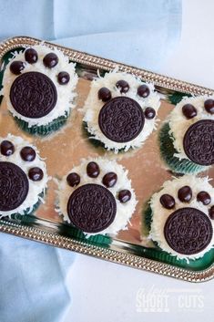 four cupcakes decorated with oreo cookies and white frosting on a tray