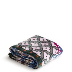 two blankets folded on top of each other in front of a white background with blue, pink and green designs