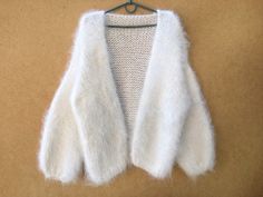 a white knitted sweater hanging on a clothes hanger, with the top section partially open