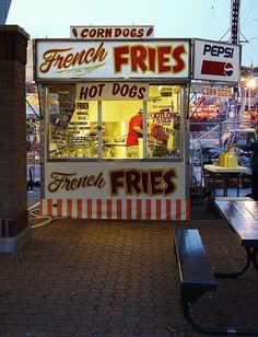 a hot dog stand with french fries on the side