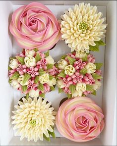 pink and white flowers in a box with green leaves on the top one flower has been made from fondant