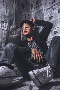 a young man sitting on the floor wearing glasses