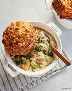 a white bowl filled with chicken pot pie soup and a wooden spoon next to it