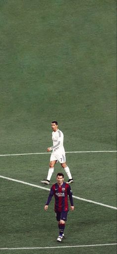 two men playing soccer on a field with one jumping in the air and another running