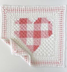 a crocheted blanket with a red heart on the front and white squares on the back