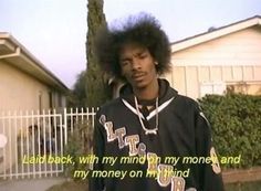 a man with an afro standing in front of a house