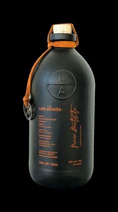 a large black bottle with an orange label on the top and brown leather strap around it