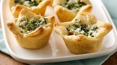 mini quiches filled with spinach and cheese on a white plate next to a blue napkin