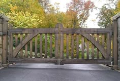 an open wooden gate with stone walls and trees in the background