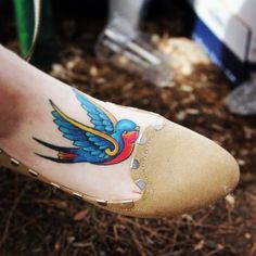 a person's foot with a bird tattoo on it and the bottom part of their shoe