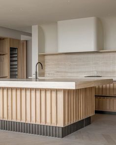 a large kitchen with an island in the middle and wood paneling on the walls