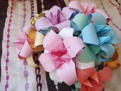 a bunch of different colored paper flowers on a tablecloth with chains and circles in the background