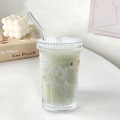 a glass cup with a straw in it sitting on a table next to a book