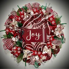 a red and white wreath with the word joy written on it, surrounded by christmas decorations