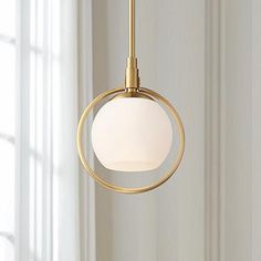 a light fixture hanging from the ceiling in a room with white walls and curtains behind it