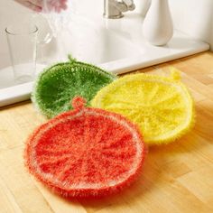 three pieces of felt sitting on top of a wooden table next to a faucet