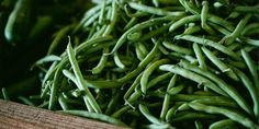 green beans are piled on top of each other in a wooden box, ready to be sold