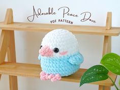 a crocheted bird sitting on top of a wooden shelf next to a plant