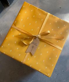 a yellow gift box wrapped in gold paper with white polka dots