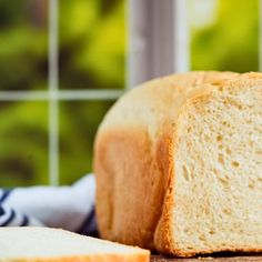 a loaf of white bread sitting on top of a table next to a slice of bread