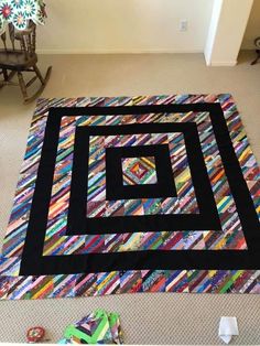 a black and white quilt sitting on top of a floor next to a rocking chair