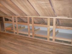 an attic with wooden flooring and unfinished walls