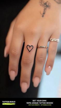 a woman's hand with a small heart tattoo on her left thumb and finger