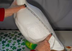 someone is measuring the fabric on a white pillow with green and red trimmings