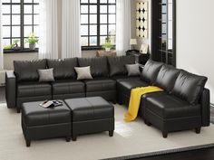 a living room with black leather couches and ottomans