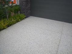 a garage door is open in front of a house with plants on the side walk