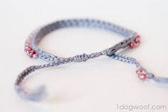 two bracelets with red beads are shown on a white surface, one is gray and the other is grey