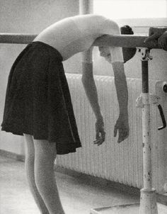 a woman bending over to look at something on the floor next to a radiator