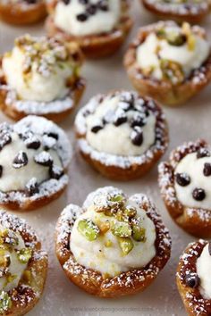 many small pastries are covered with powdered sugar and pistachio toppings