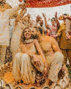 people are throwing orange powder on each other in the air as they pose for a photo