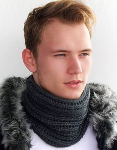 a young man wearing a gray scarf and black jacket with his hair in a pony tail